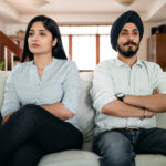 Offended young indian couple sitting on sofa